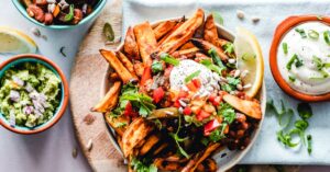 A vibrant platter of savory sweet potato fries with fresh toppings, perfect for a tasty snack.